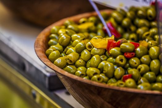 Close-up of green olives with red and yellow pepperoni in a dish