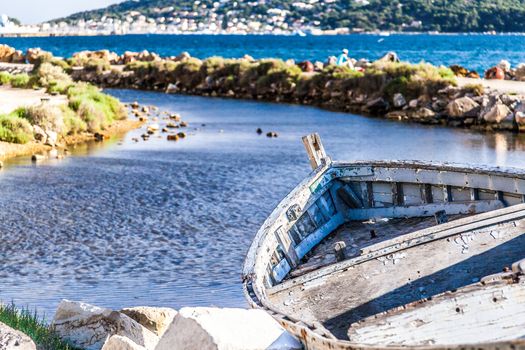 aged and abandoned fishing boats laying on the shore closed to a old tower in france