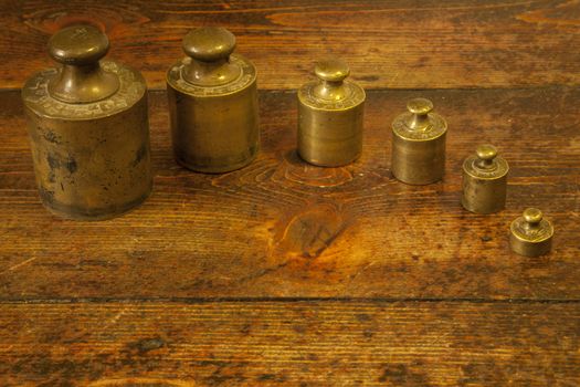 Different vintage brass weights unit on wood floor background