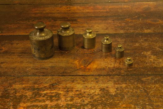 Different vintage brass weights unit on wood floor background