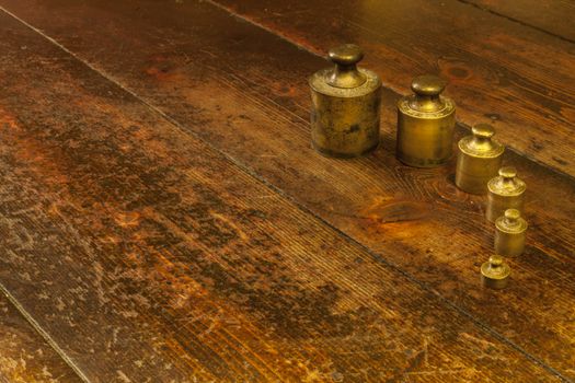 Different vintage brass weights unit on wood floor background