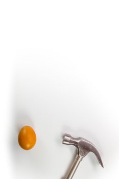 Hammer hitting a egg isolated on white with copy space.