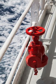 Red fire extinguisher with pipe connector on a boat