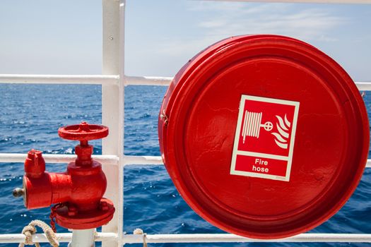 Red fire extinguisher with pipe connector on a boat