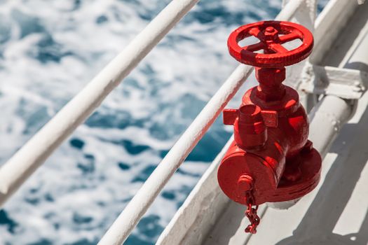 Red fire extinguisher with pipe connector on a boat with waves