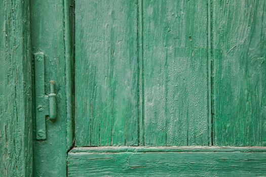 Recently painted green wood door and window panels with hinge