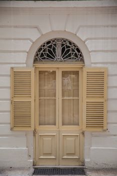 An old weathered french window with opened shutters