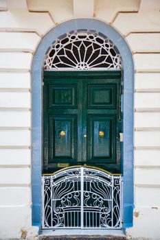A geen wood door with white small fence and blue frame