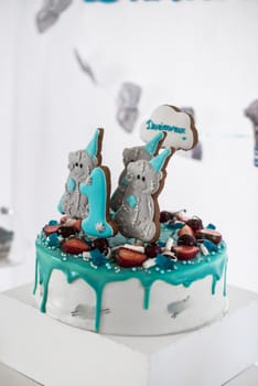 White cake decorated with blue fondant and cookies in the form of bears
