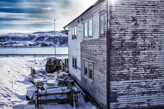 Weathered house covered by snow in front of the norwegian sea