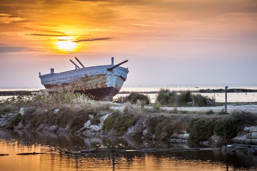 An old and weathered boat at the sicilian sunset