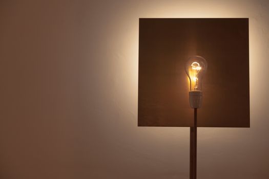 A lamp made with a lamp over a square shaped copper background