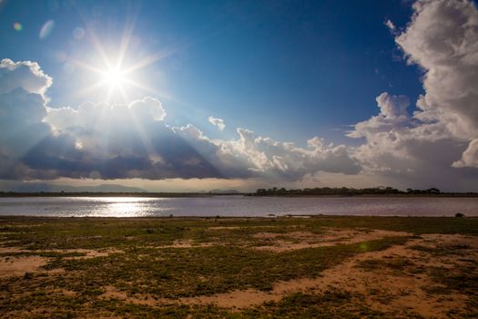 A typical african view of an afternoon sun with a lake and clouds