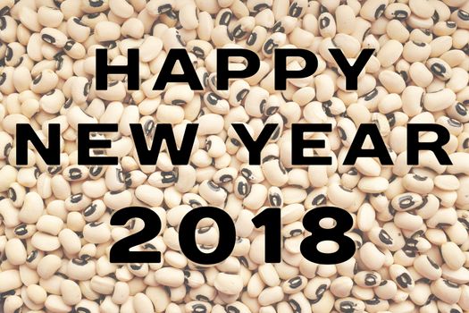 HAPPY NEW YEAR 2018 text written over a dried black eyed beans background, food considered to bring luck