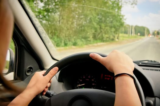 Woman driving, view inside a car on a road