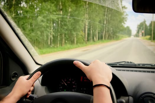 Woman driving, view inside a car on a road