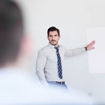 Business man making a presentation at office. Business executive delivering a presentation to his colleagues during meeting or in-house business training, explaining business plans to his employees.