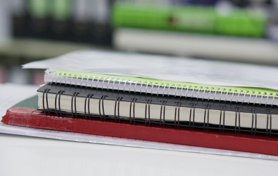 Stack of notebook and file document on white desk at office.