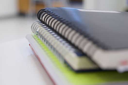 Stack of spiral notebook and accounting note on white desk at office.
