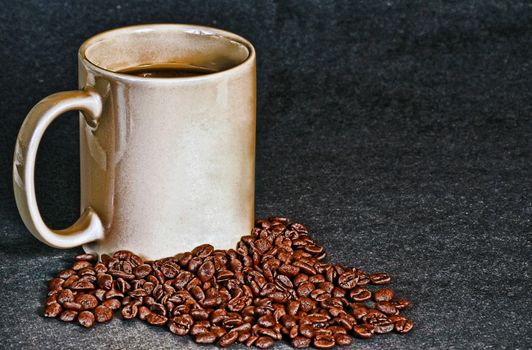 A cup of fresh ground coffee surrounded by extra beans