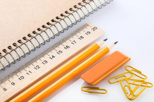 notebook, eraser, ruler, pencil and paperclips on white background