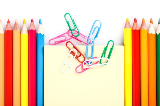 set of colored pencils and paper clips on a white background
