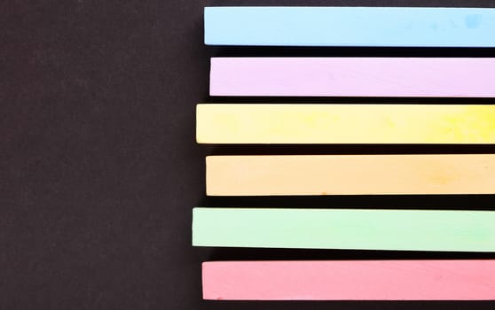 set of colored crayons on a black background