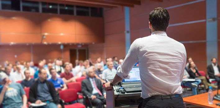 Speaker giving a talk on corporate Business Conference. Audience at the conference hall. Business and Entrepreneurship event.