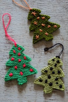 Knitted xmas tree on wooden background, Christmas trees knit from green yarn for holiday season