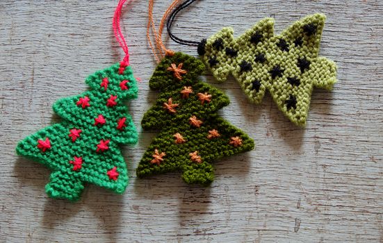 Knitted xmas tree on wooden background, Christmas trees knit from green yarn for holiday season