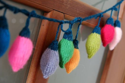 Group of colorful Xmas ornament for winter holiday, handmade product, knitted Christmas lights bulb hang on door