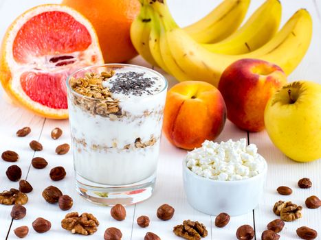 Healthy breakfast: cottage cheese and yogurt with muesli and chia seeds, fruits and nuts on white wooden background. Dieting, healthy lifestyle concept meal