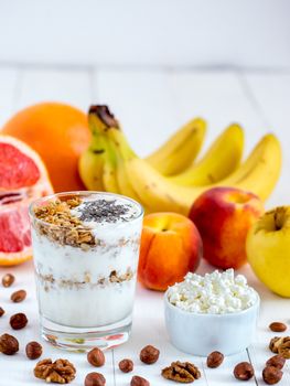 Healthy breakfast: cottage cheese with yogurt, fruits and nuts on white wooden background. Dieting, healthy lifestyle concept meal. Vertical with copyspace