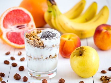 Healthy breakfast: yogurt with muesli and chia seeds, fruits and nuts on white wooden background. Dieting, healthy lifestyle concept meal