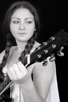 Beautiful woman with a guitar on a black background