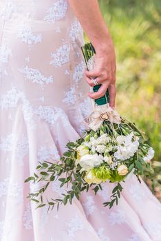 wedding bouquet in hands of the bride on background of the dress