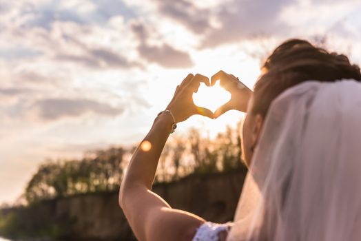 the bride shows a sign of heart at sunset