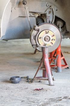 Front disk brake on car in process of damaged tyre replacement. The rim is removed showing the front rotor and caliper.