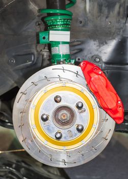 Front disk brake system on car in process of damaged tyre replacement. The rim is removed showing the front rotor and caliper.