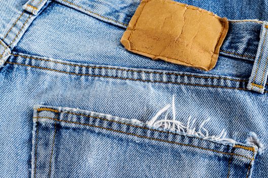 Close up back pocket and brown leather tag of old denim jean background.