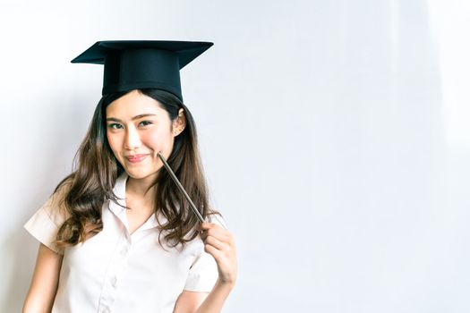 Beautiful asian university or college graduate student woman wearing mortar board, doing cute pose in front of shiny whiteboard, with copy space