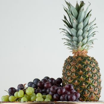 Ananas and green, red grape isolated on white.