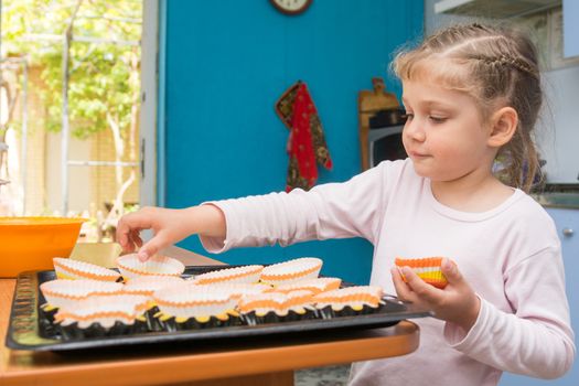 The child lays on a baking tins Easter cupcakes