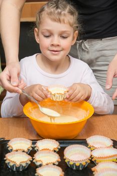 Daughter holds the mold for the cake, while my mother draws the dough from the bowl