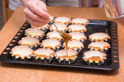 Boiled condensed milk added to raw cupcakes workpiece lying on a baking sheet