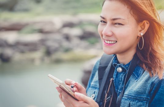 Asia Woman using a cell phone with a smile and good humor.