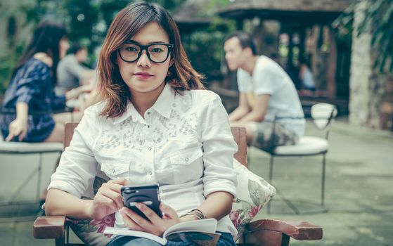 Asian woman taking notes on the phone with the intention.
