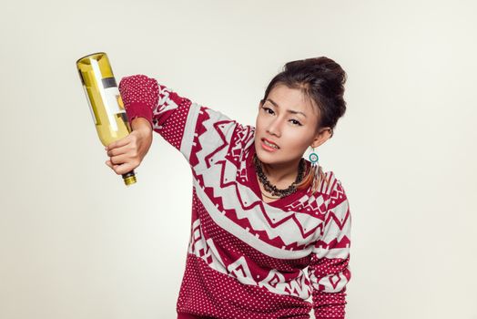 Asian woman holds up an empty bottle, mood wondering.