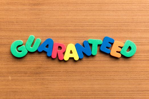 guaranteed colorful word on the wooden background