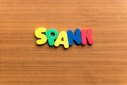 spank colorful word on the wooden background